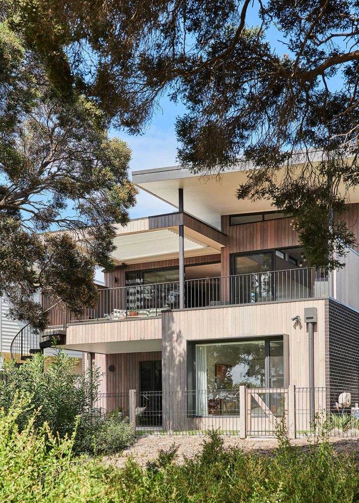 Architecturally designed custom home in Barwon Heads featuring natural timber cladding, large windows, and native bush landscaping.